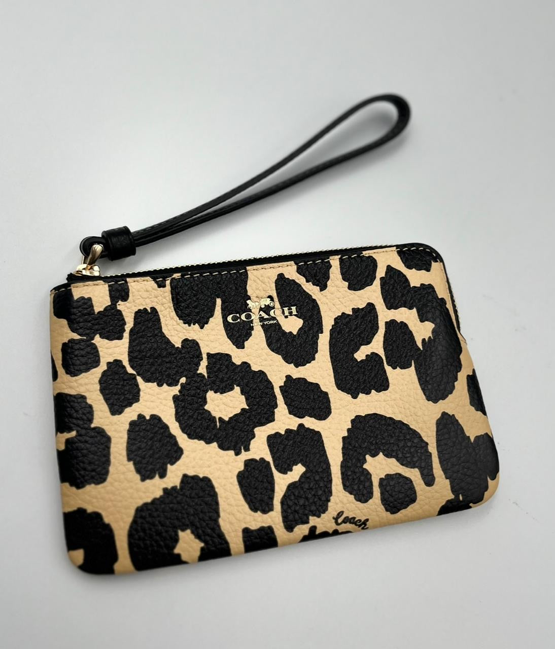 Coach muñequera Corner Zip Wristlet con estampado de leopardo.