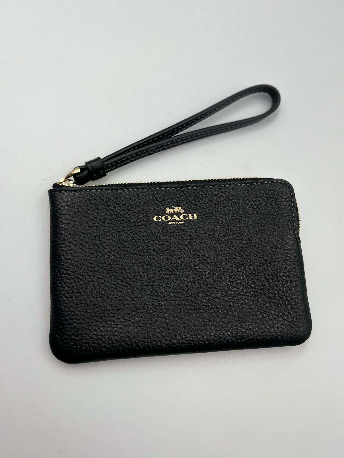 Coach Muñequera 
modelo Double Corner Zip Wristlet.